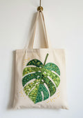 Monstera Leaf Appliqué Tote Bag hanging on a wall hook